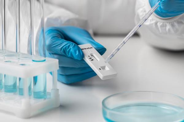 A person holding a test tube in front of some petri dishes.