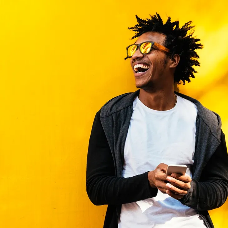 A man with dreadlocks holding his cell phone.
