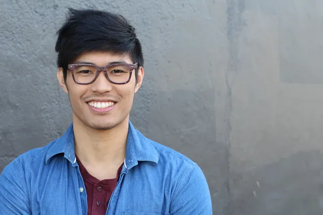 A man with glasses smiling for the camera.